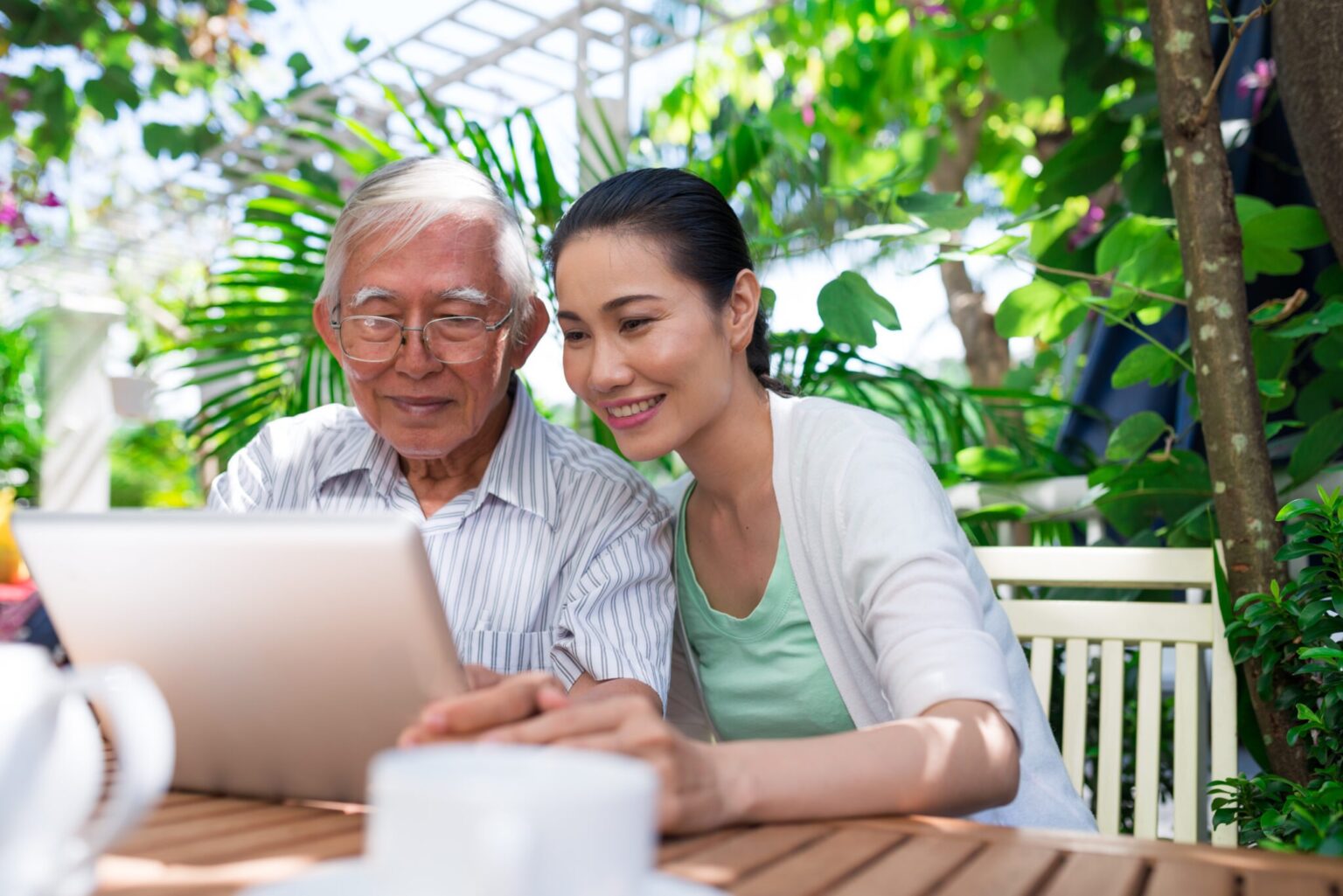 elderly man looking at a laptop with his daughter